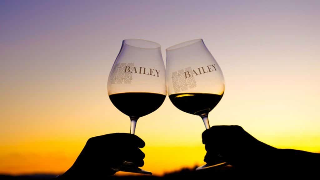 Two logo Pinot noir glasses toasting at sunset