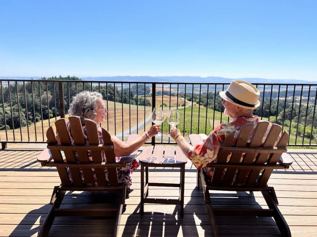 10 Best Wineries in the Willamette Valley to Try in 2023, photo of a happy couple enjoying the spectacular vineyard views at Youngberg Hill Inn 